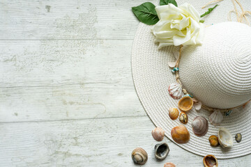 summery scene with pamela hat on white wooden background with shells and copyspace