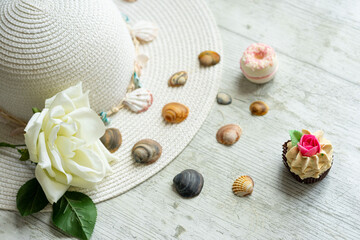 summery scene with pamela hat on white wooden background with shells and copyspace