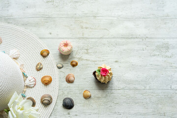 summery scene with pamela hat on white wooden background with shells and copyspace