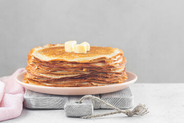 Stack of hot crepes with pieces of butter. On white table. Copy space.