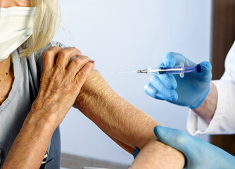 85-year-old woman receives the covid-19 vaccine from a doctor at home. Vaccination of the elderly.