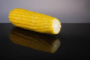 Cooked sweet corn with reflection on glass table