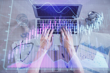 Double exposure of woman hands working on computer and forex graph hologram drawing. Top View. Financial analysis concept.