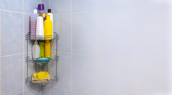 A Metal Bathroom Grate Shelf Filled With Body And Hair Care Products Weighs On A Blue Tile In The Corner.