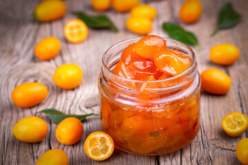 Homemade kumquat jam in jar and fresh kumquats, top view