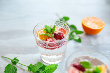 Summer cocktail with strawberry, orange and mint in glass