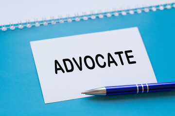 Written words ADVOCATE on paper notebook on BLUE background.