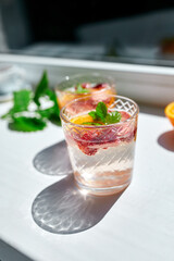 Summer cocktail with strawberry, orange and mint in glass