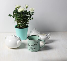 Still life with Beautiful day blue cup of tea, pot, sugar, white roses plant