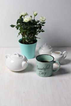 Beautiful day blue cup with tea, pot, sugar, white roses plant