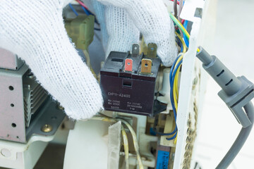 Technician repair microwave oven, Checking microwave oven reley, Home appliances repair service.
