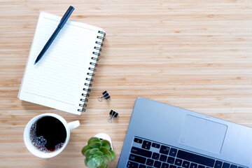 flat lay composition with notebook, pen, coffee, plant, laptop on wood background.