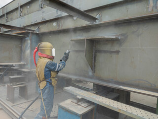 Worker is sandblasting a welding surface and steel structure with pressure blasting pot for create surface profile of steel before painting.