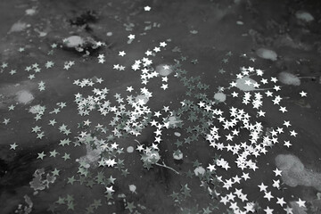 
texture of gray concrete with spots of white paint and silver confetti stars. moon surface