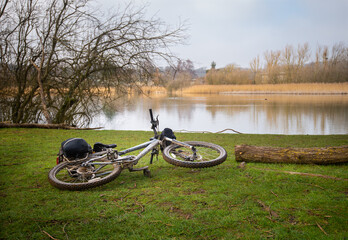 Fototapeta na wymiar Bicycle on ground beside clear lake on winter's day near Chartham in Kent