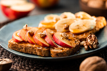 Toasts with peanut butter, apple, banana, walnut and honey. Healthy vegetarian breakfast concept.