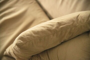 beige pillow on the corner of a couch sofa crumbled