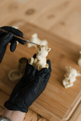 confectioner in gloves on the table makes edible animals