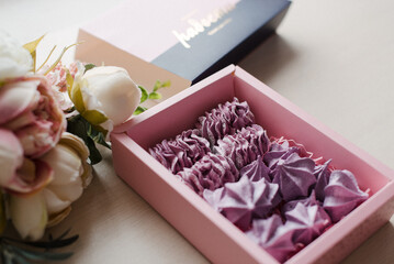 pink meringue and flowers in a box on the table close-up