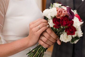 Obraz na płótnie Canvas hands of bride and groom and wedding bouquet close-up