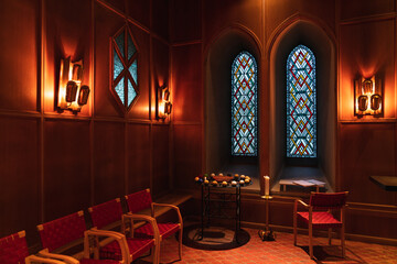 This deep red church interior has a religious and ominous feel, almost cultist in it's presentation. Blue stained glass windows and an alter sits in the middle of the shot.