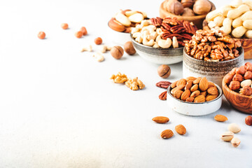 Assortment of nuts in bowls. Cashews, hazelnuts, walnuts, pistachios, pecans, pine nuts, peanuts, macadamia, almonds, brazil nuts. Food mix on gray background, copy space