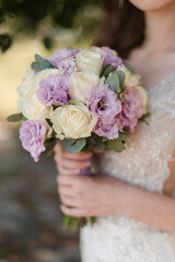 hand of the bride in a white dress and a wedding bouquet close-up