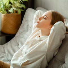 Happy calm young woman relax sitting on comfort couch at home interior. Teen girl resting, bliss...