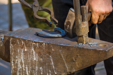 blacksmith performs the forging of hot glowing horseshoe on the anvil