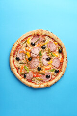 Italian Pizza with homemade sausage, Mozzarella, Bulgarian pepper, Olives, Small cucumbers, Champignons, Oregano. Blue background. Copy Space