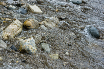 pebble stones on the sea beach, the rolling waves of the sea with foam