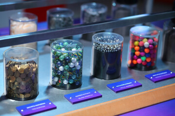 Glass containers with different stones, marbles  and coins on a laboratory table