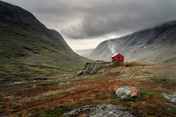 A single small red cabin billows smoke from it's tiny chimney in the remote gorge of central...