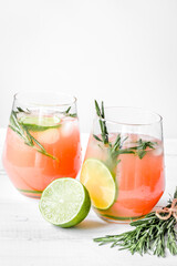 sliced lime, rosemary and natural juice in glass on white table background