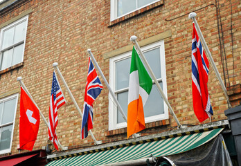 Flags of Switzerland, United States, Great Britain, Ireland and Norway on a travel agency awning on a brick building