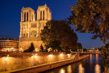 Fototapeta na wymiar Notre Dame de Paris cathedral illuminated at dusk in summer with the Seine River banks (UNESCO World Heritage Site). Ile de la Cite, Paris, France