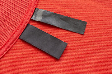 Blank black laundry care clothes label on red fabric texture background