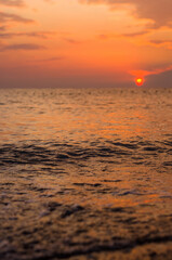 Amazing sea sunset on the pebble beach, the sun, waves, clouds