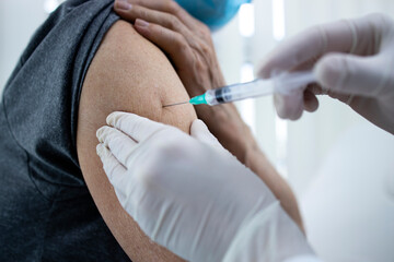 Close up view of an elderly man getting vaccine shot in his arm during corona virus pandemic.