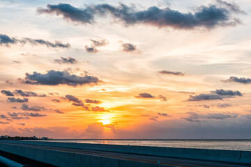 Sunrise in Islamorada, Florida keys with orange colorful sky by overseas highway road bridge at Gulf of Mexico with clouds in cloudy sky