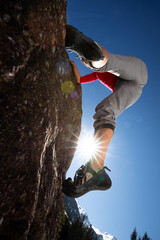 Young female climber  climbing on a boulder outdoors, in Swiss Alps