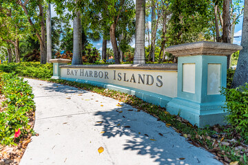Bay Harbor Islands sign for Miami Dade County, Florida by Biscayne Bay in public park with paved path and nobody by palm trees