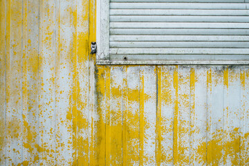 detail view on closed window and yellow weathered wall