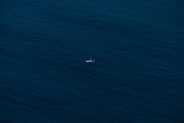 alone woman or girl in the ocean riding and posing on a stand up paddle board (SUP) - sport paddle activity.