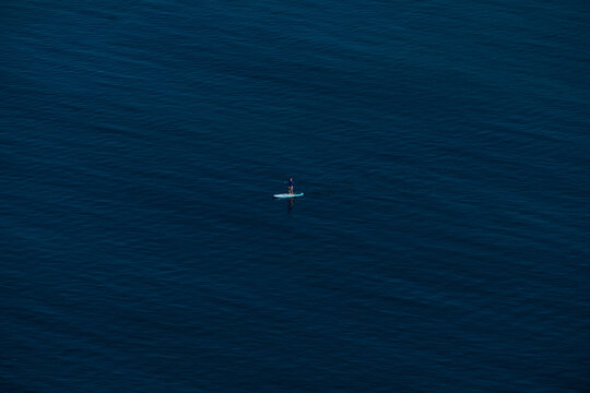 alone woman or girl in the ocean riding and posing on a stand up paddle board (SUP) - sport paddle activity. © Alessandro