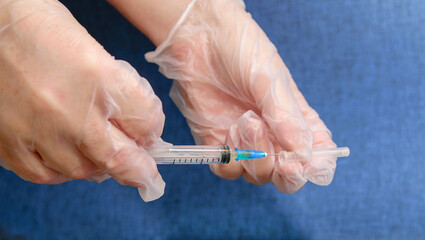 Nurse holds syringe for injection and removes cap from syringe