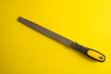 Metal file on a yellow background with traces of dirt
