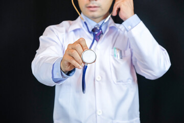Portrait of confident young medical doctor on black background. He using stethoscope.