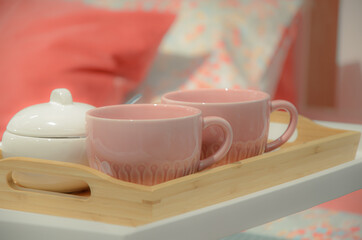 Two big pink cup of tea and white sugar bowl on wooden tray. Breakfast in bed. Symbol of romantic morning for a couple of lovers. Soft mist effect
