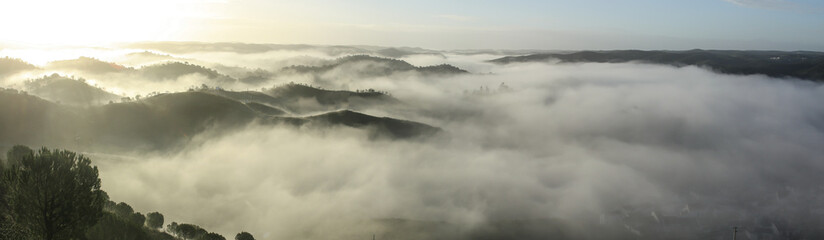 Vista panorámica de colinas envueltas en niebla al amanecer en Sanlúcar de Guadiana, Huelva, Andalucía, España.